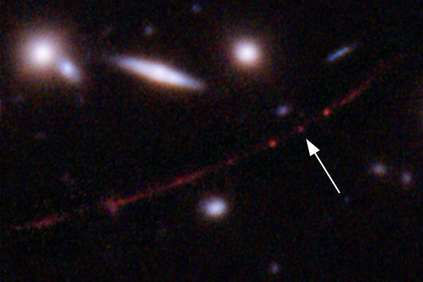 This image made available by NASA on Wednesday, March 30, 2022, shows the star Earendel, indicated by arrow, and the Sunrise Arc galaxy, stretching from lower left to upper right, optically bent due to a massive galaxy cluster between it and the Hubble Space Telescope which captured the light. The mass of the galaxy cluster serves as a magnifying glass, allowing Earendel to be seen. (NASA, ESA, Brian Welch (JHU), Dan Coe (STScI); Image processing: NASA, ESA, Alyssa Pagan (STScI) via AP)