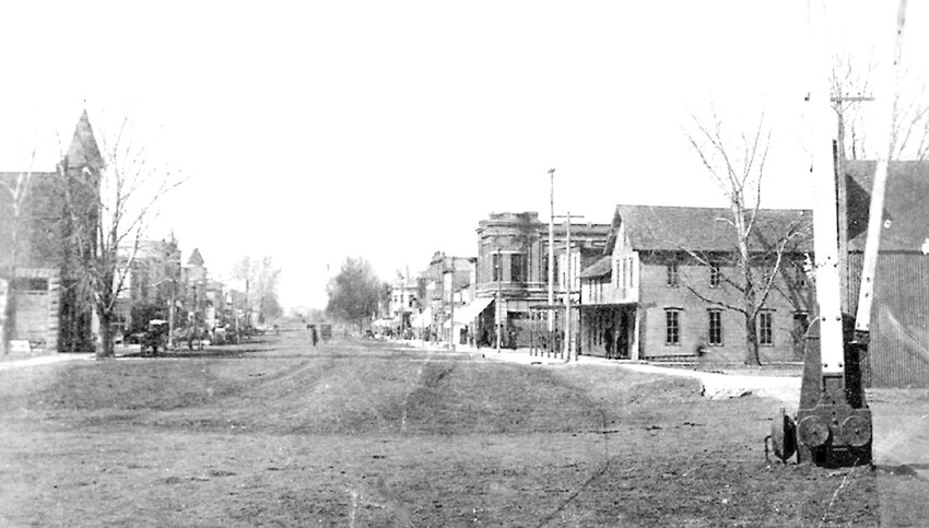 Looking north on Brookings Main Street from the railroad tracks in early 1900. Note the hand operated railroad crossing barrier at right. Also at right is the Brookings House Hotel, which burned in 1916. Get Busy Club member C. A. Skinner built the brick building seen behind the Brookings House. Today a bar in that building is named after Skinner. The 1894 Masonic Temple building, where the Get Busy Club held its meetings, is at left.