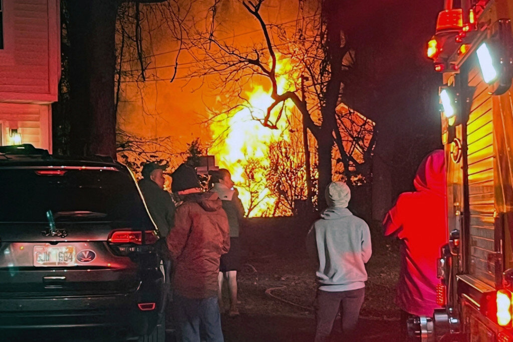 Flames are seen at a distance where a home exploded on Monday night in Arlington, Va. Officials are investigating the circumstances surrounding a massive explosion that destroyed a duplex and shook a Virginia suburb of Washington, D.C. (AP Photo/Emily Saxon)
