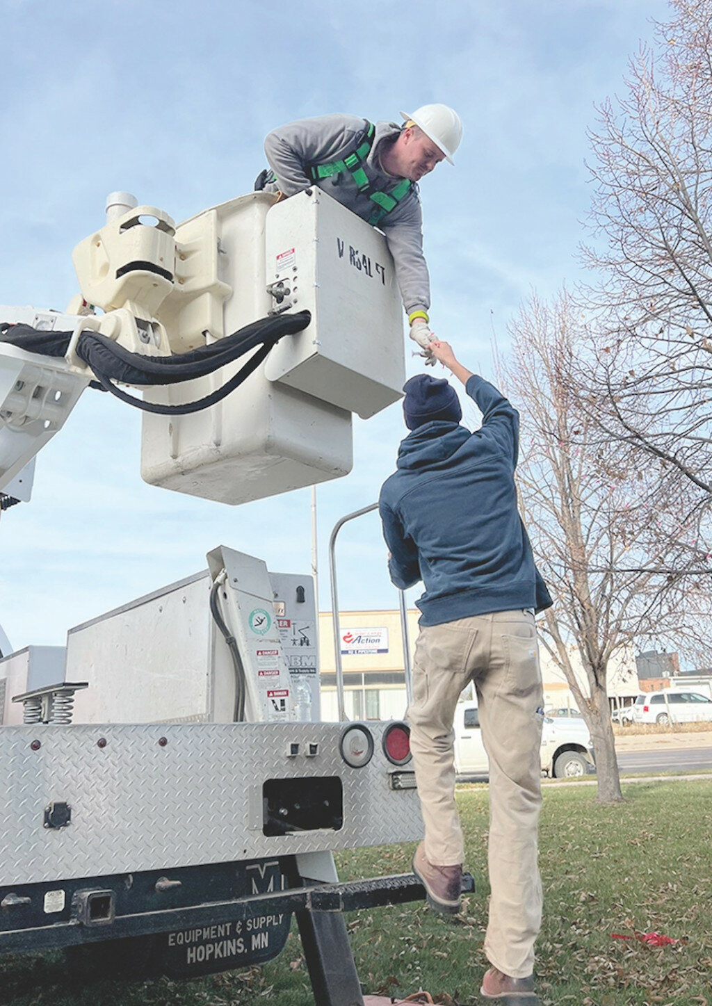 The weather couldn’t have been better this past week for volunteers, local business leaders, and city employees, to string up holiday lights in early November. Temperatures hovered around 50 degrees throughout the day. Jaymes Zollner, new in the past year to the team with the City of Flandreau electrical department, handed light strings to Ryan Sherman, Flandreau City Electrical Supervisor as the two went tree by tree down the front walkway of the County Courthouse.