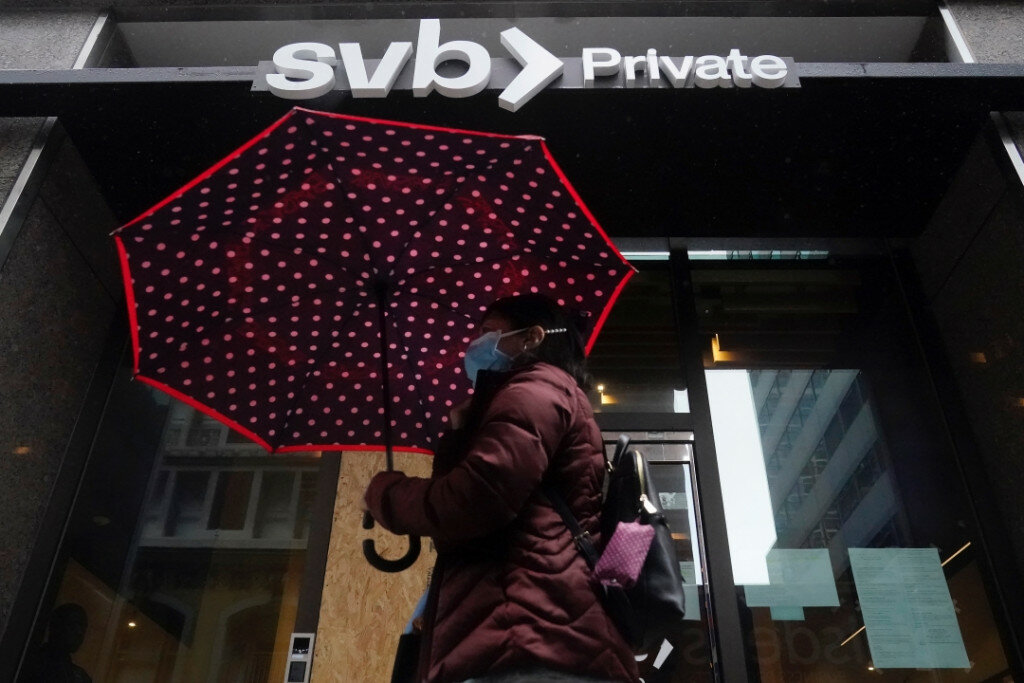 A pedestrian carries an umbrella while walking past a Silicon Valley Bank Private branch in San Francisco on Tuesday. (AP Photo/Jeff Chiu)
