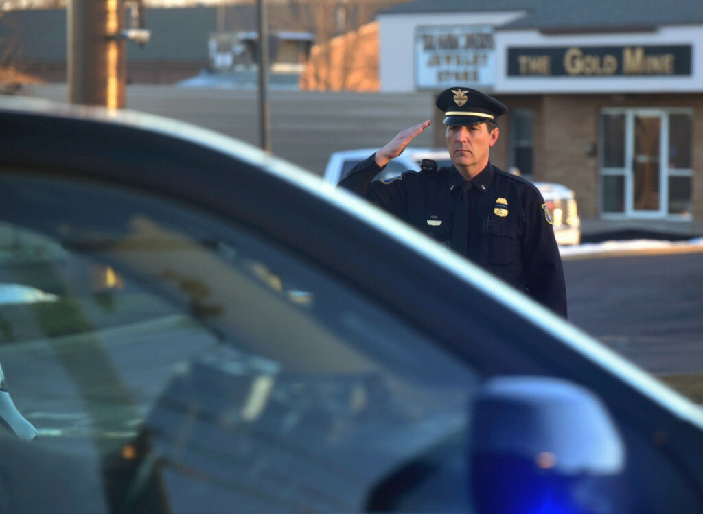 Sioux Falls Police Lt. Andrew Siebenborn salutes a passing law enforcement procession carrying the remains of Moody County Chief Deputy Sheriff Kenneth Prorok on Monday in Sioux Falls. Prorok was killed Friday after being struck by a car while putting out spikes during a police chase following an attempted traffic stop. (Dominik Dausch/The Argus Leader via AP)