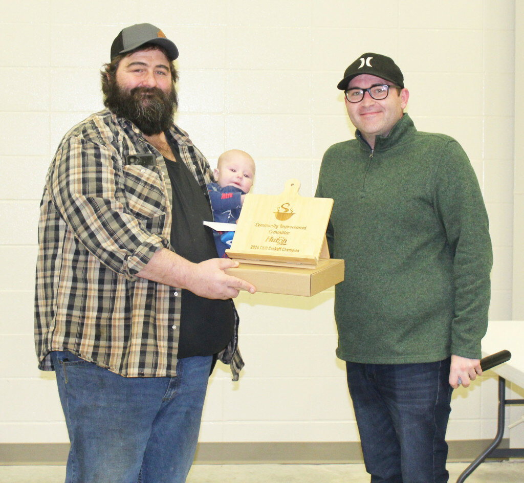 PHOTOS BY ROXY STIENBLOCK/PLAINSMAN
Jason Cashman, holding his son, John Cashman, is presented the award Saturday for winning the Winterfest Chili Cook off by City Commissioner Drew Weinreis.