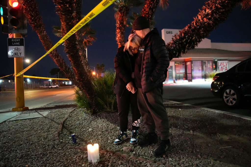 Sean Hathcock, right, kisses Michelle Ashley after the two left candles for victims of a shooting at the University of Nevada, Las Vegas, on Wednesday in Las Vegas. The two graduated from the school and live nearby. (AP Photo/John Locher)