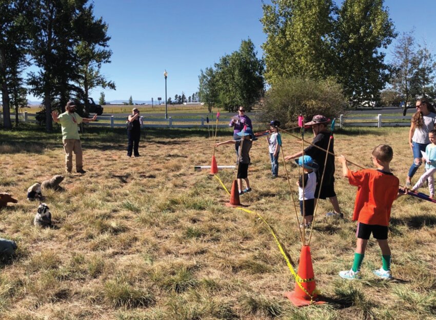 Young participants learn to throw atlatls at targets.