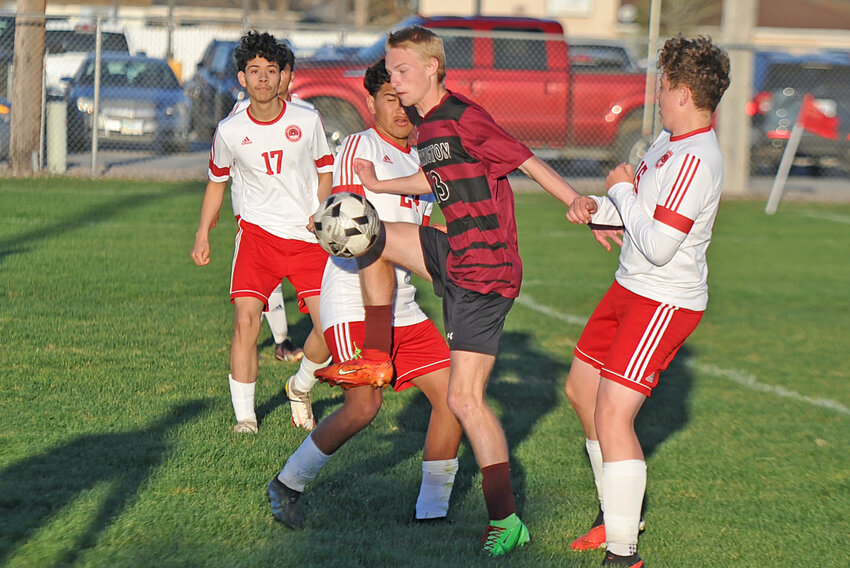 Junior Elijah Hatch, center, keeps the ball away from his Scottsbluff opponents during the April 16 home game.