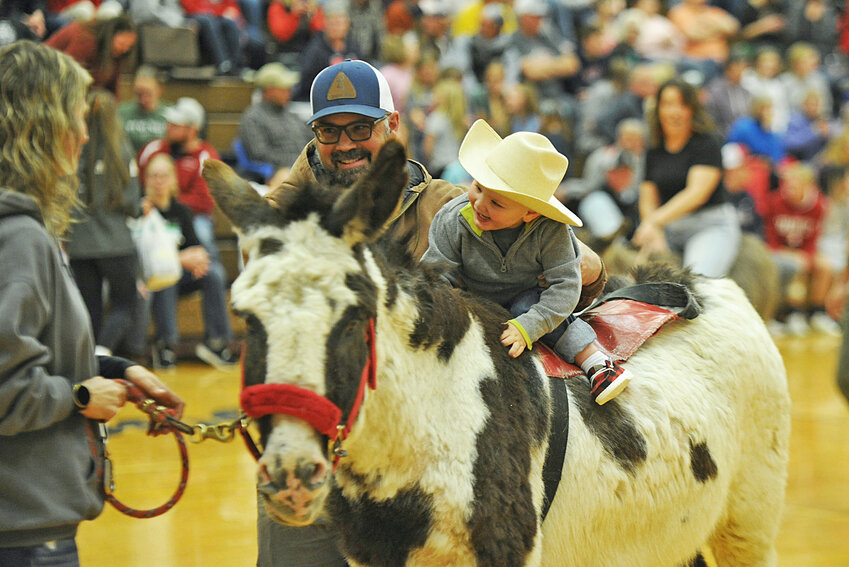 Young Locklynn Grant enjoys a ride on one of Dairyland Donkeyball’s rides as his father, Justin Grant, provides balance.