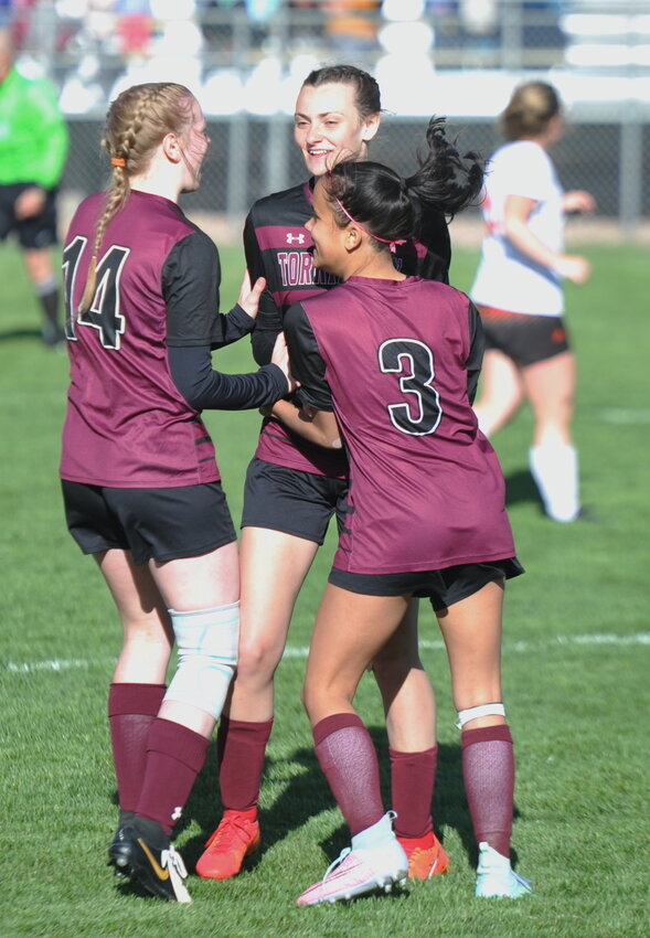 Sophomores Allie Martinez and Kynzi Thomas congratulate sophomore Kennedi Blevins on scoring a big goal for Torrington in the second half.
