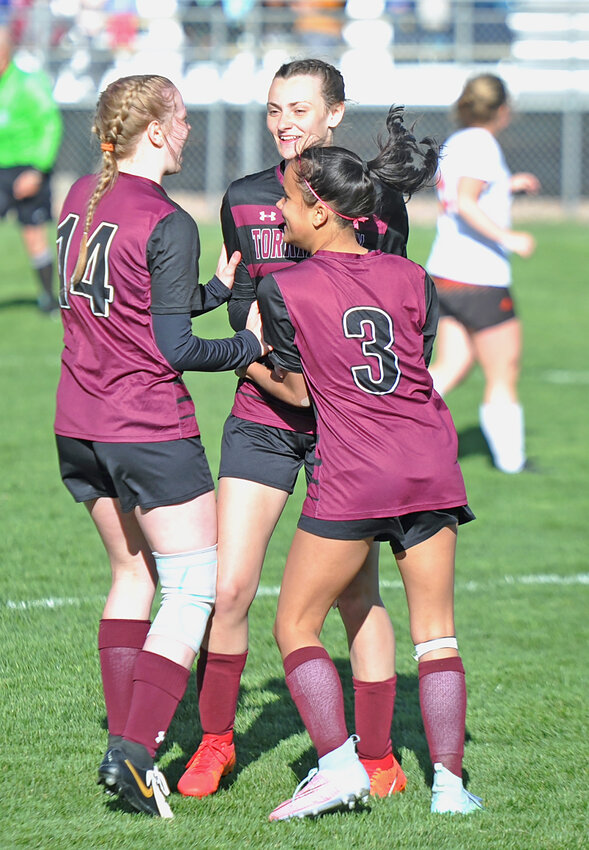 Freshman Kynzie Thomas, No. 14, and sophomore Allie Martinez, No. 3, congratulate sophomore Kennedi Blevins, center, for scoring her goal against Newcastle on May 2.