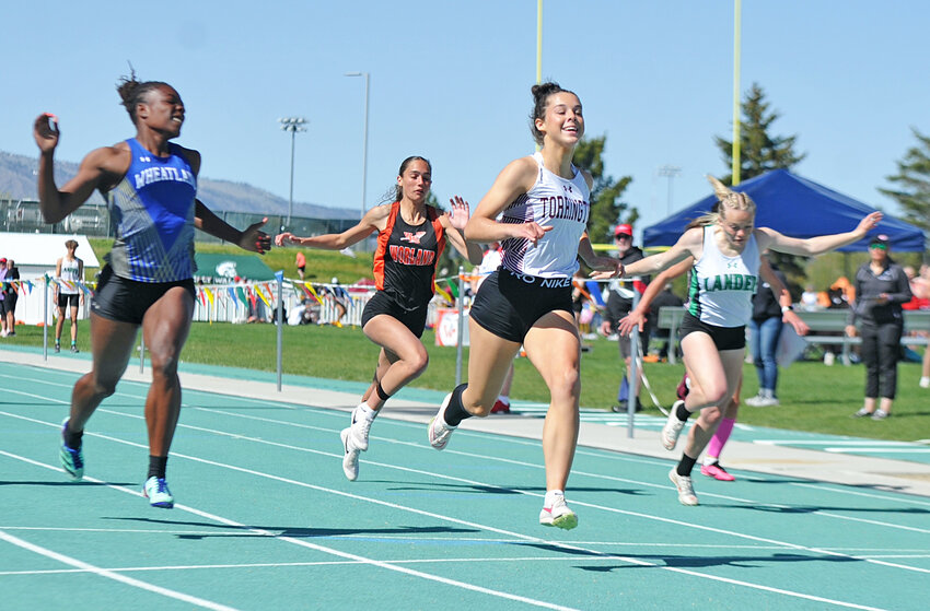 Sophomore Brooklyn Asmus crosses the finish line with smile in the 100-meter finals on Saturday. Asmus won the 100-, 200- and 400-meters and broke the 3A class records in the 100- and 200-meters. Asmus tied the Wyoming all-classification record in the 100-meters.