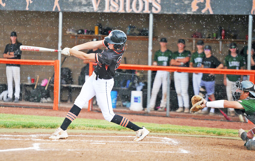Mac Hibben singles as rain begins to fall during the July 20 district playoff win against Wheatland. Hibben had four hits over the course of the double header.