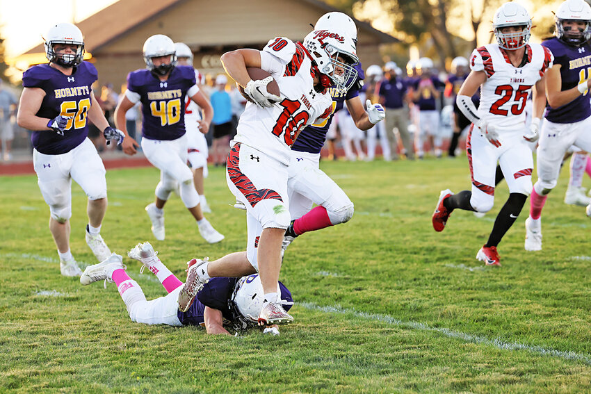 Senior Ridge Kupke, No. 10, breaks tackle to drive the ball forward for the Tigers against the Hornets on October 4. Also pictured is junior Cody Himes, No. 25.