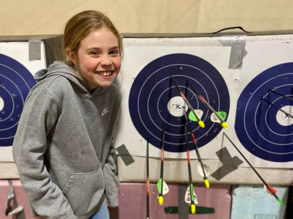 Addalyn Souza poses next to her second-place winning shoot as she scored 295 points in the 2023 Platte County archery shoot contest.