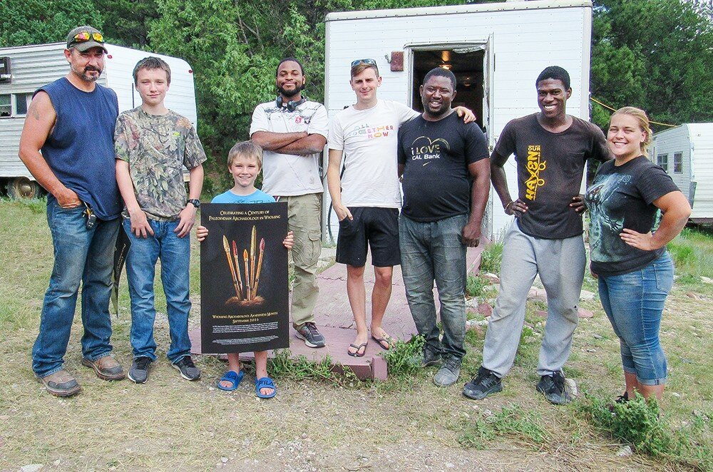 Young Caleb Dawson proudly displays the Anthropology poster he was given during the July 2019 end-of-field school open house at the Hell Gap site. He was accompanied by his father, Edward Dawson, far left, and brother Emmett Dawson, of Hartville, Wyo. Field school students from left to right are Sashuan Armbrister, Scotia Mullin, Evans Atuick, Kody Rolle and Jessica Wriedt, a student at Northern Colorado University at Greeley.