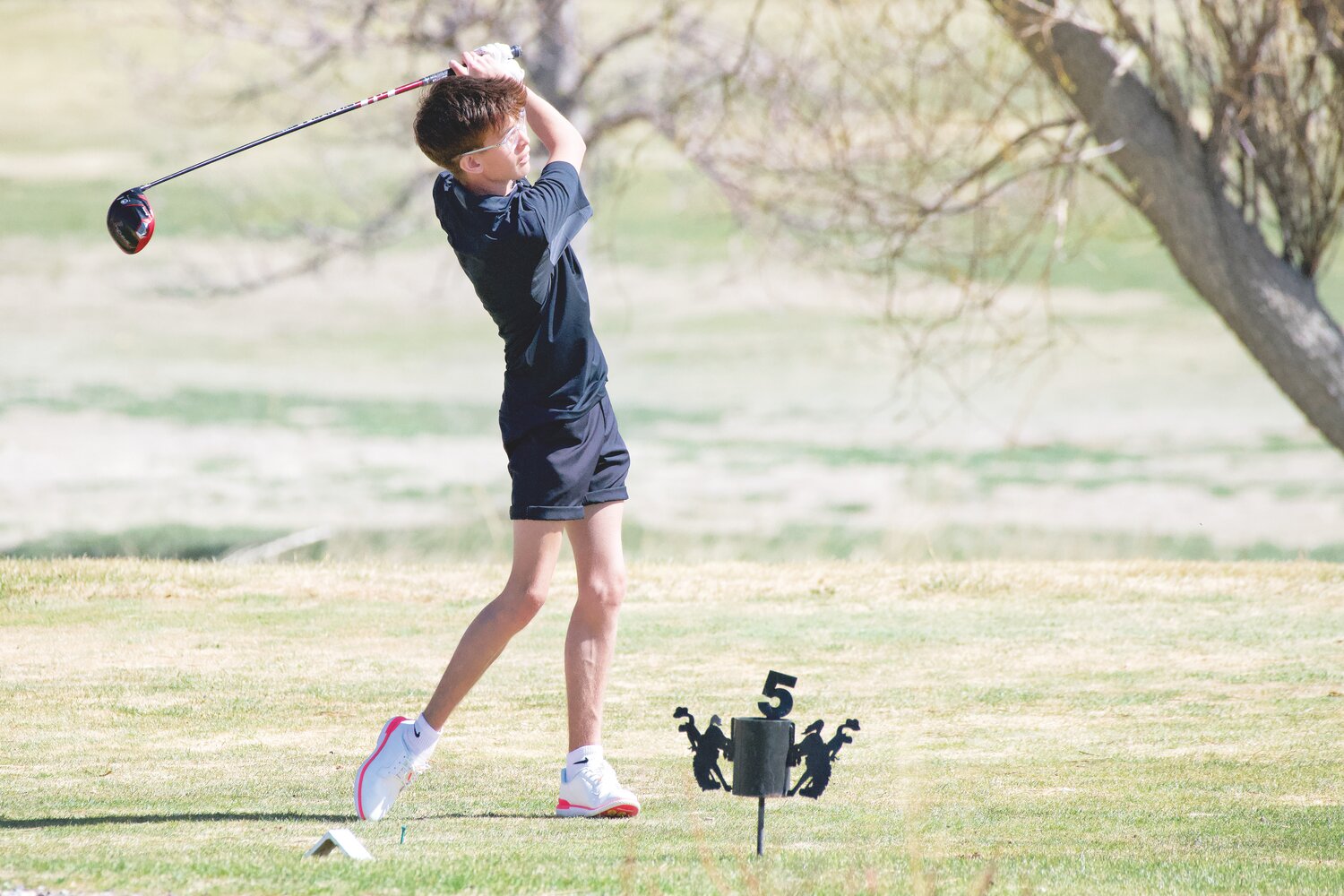 Isaac CdeBaca tees off on hole number five at Wheatland Golf Course during the first golf match of the season.