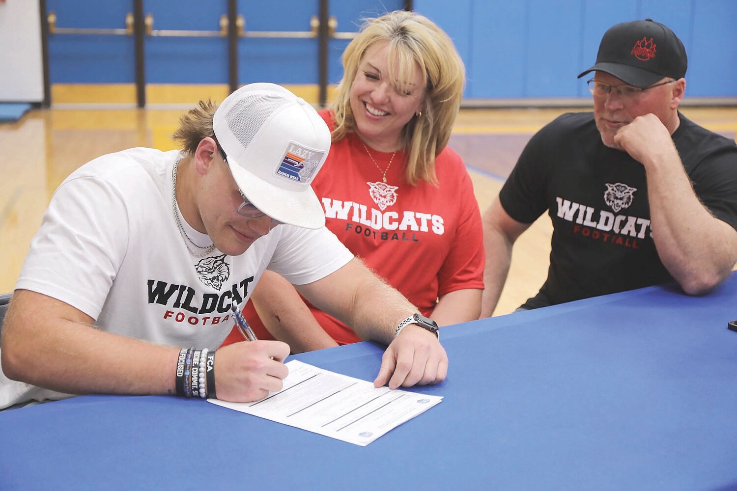Bode Stone signs a national letter of intent to play football for North Dakota State College of Sciences while parents Jen and Eli Stone look on.