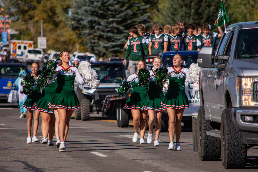 PHS cheerleaders, from left, Teagan Fildey, Victoria Ramage, Samantha McDaniel, Naomi Gaffney and Karlee Nelson, chant ‘Let’s get a little bit rowdy’ as they escort the Wrangler football team down Pine Street during the 2024 Homecoming Parade. 