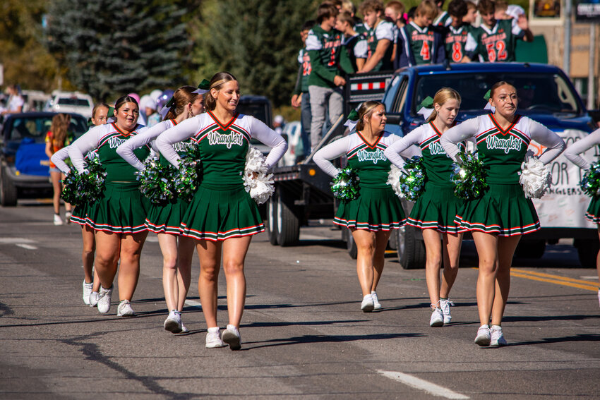 PHS cheerleaders, from left, Teagan Fildey, Victoria Ramage, Samantha McDaniel, Naomi Gaffney and Karlee Nelson, chant ‘Let’s get a little bit rowdy’ as they escort the Wrangler football team down Pine Street during the 2024 Homecoming Parade. 