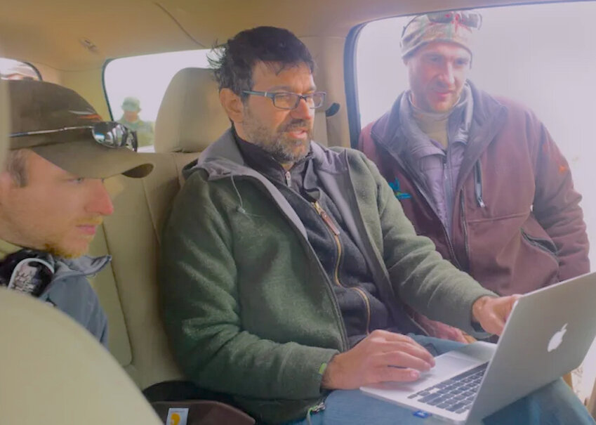 Matt Kauffman, co-founder of Wyoming Migration Initiative, takes a laptop break during a capture-and-collar operation near Big Piney in 2014. To his left is then-PhD candidate Matt Hayes and, to his right, University of Wyoming professor Kevin Monteith.