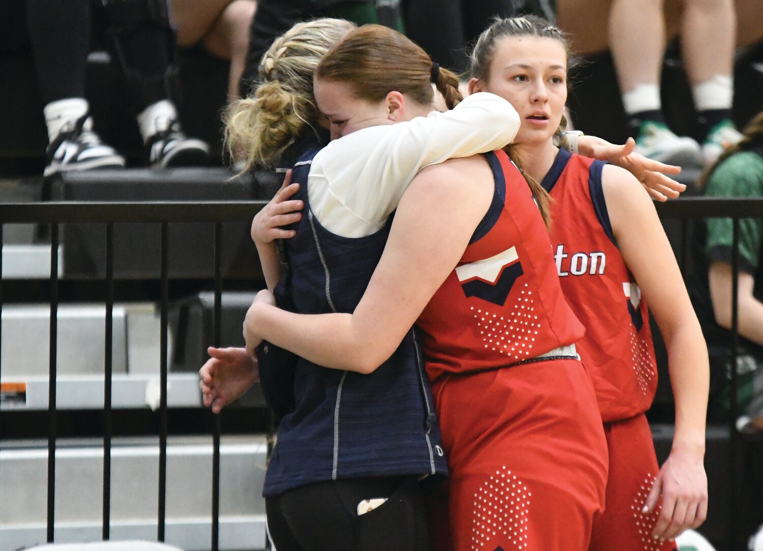 Lady Devils seniors Rhyen Debenham (left) and Jacey Bardsley are comforted by team trainer Jackie Clark, as time winds down during Evanston’s 49-29 loss to Riverton Friday in Green River. It was the final high school game for both players.
