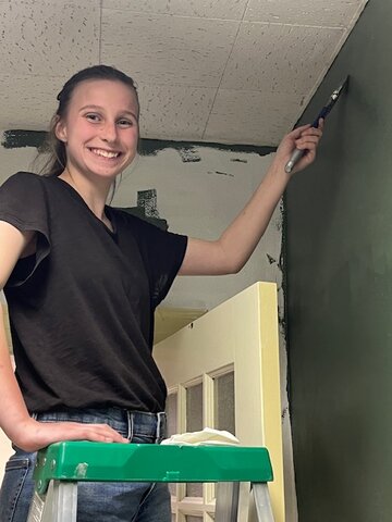 Cara Schenavar paints an interior wall at the Hamsfork Museum, an upgrade made possible by the Kemmerer Rotary Club and the KHS Interact group.