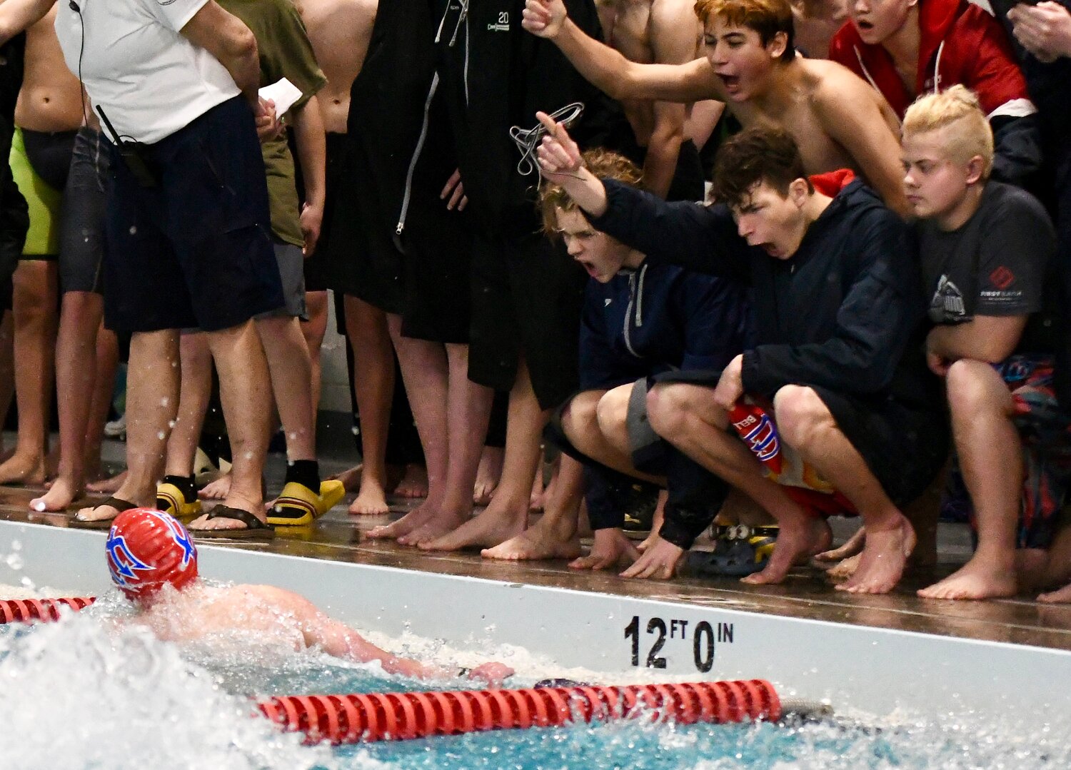 Red Devil swimmer Max Ison is cheered on by his teammates as he makes the turn during the 100 butterfly at Saturday’s 4A West Conference Championships. the Red Devils finished third as a team.