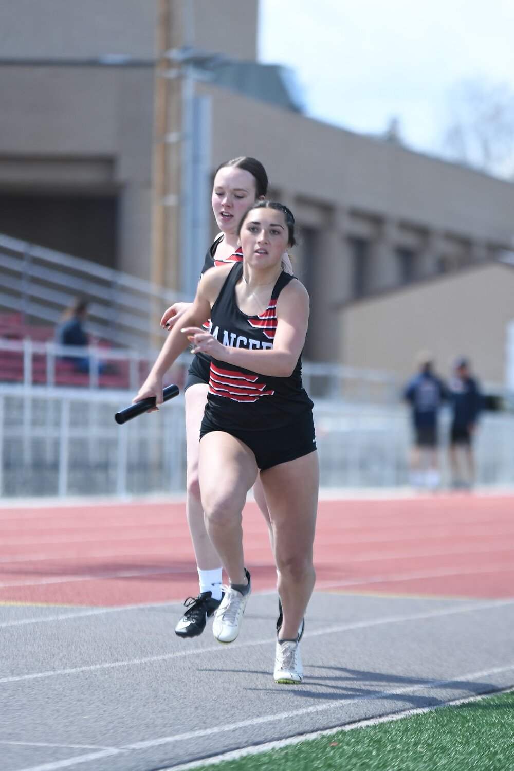 Lady Ranger Natasha Martinez takes the handoff from teammate Hadlee Wood in the sprint medley relay at last week’s Schuler Invite in Evanston. Along with teammates Jane Skidmore and Ella Thatcher, the team finished third in the event.