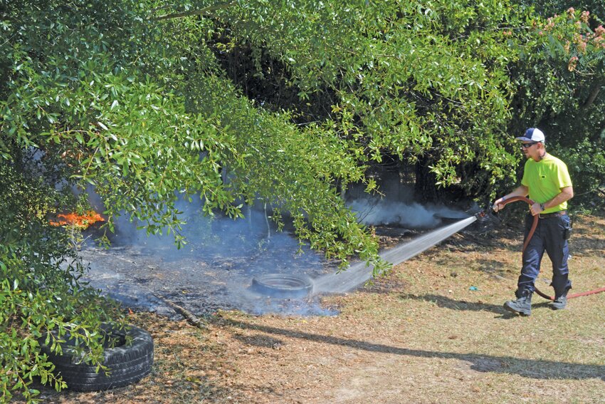 An Allendale firefighter extinguishes a brushfire near a home in Allendale County during the recent heatwave.