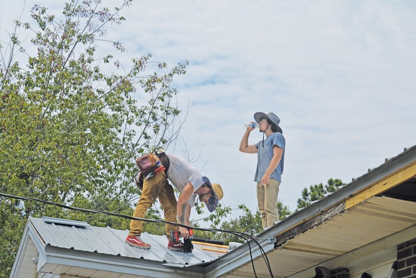 Hunter Harris, left, works on a roof while his brother Joshua, right, hydrates himself. During last week's heatwave, Hunter had to stay home for two days due to heat exhaustion.