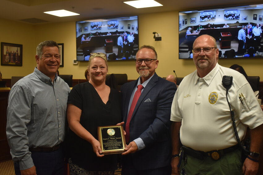 The daughter and son-in-law of the late Eugene “Buddy” Darnell accepted a plaque and a resolution of recognition in his honor. Pictured are Jodi and Doug Croft, Mayor Ron Still, and Chief Michael Butts. 