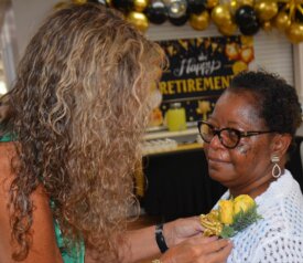 Angela Cotton pins a flower on Geronia Johnson in celebration of her retirement.