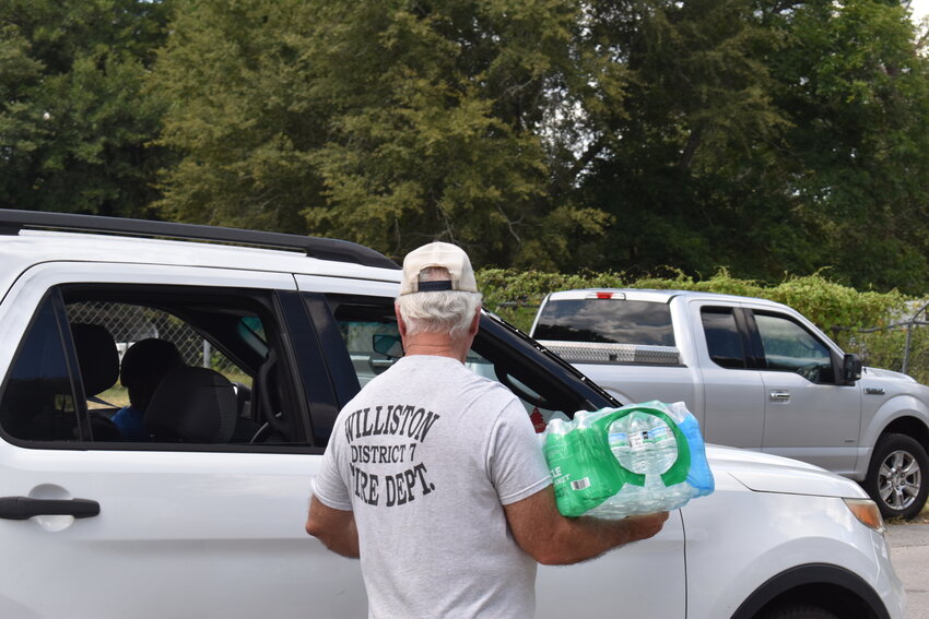 Williston Police Captain Roger Kaney helps load a case of water into a resident's car. 