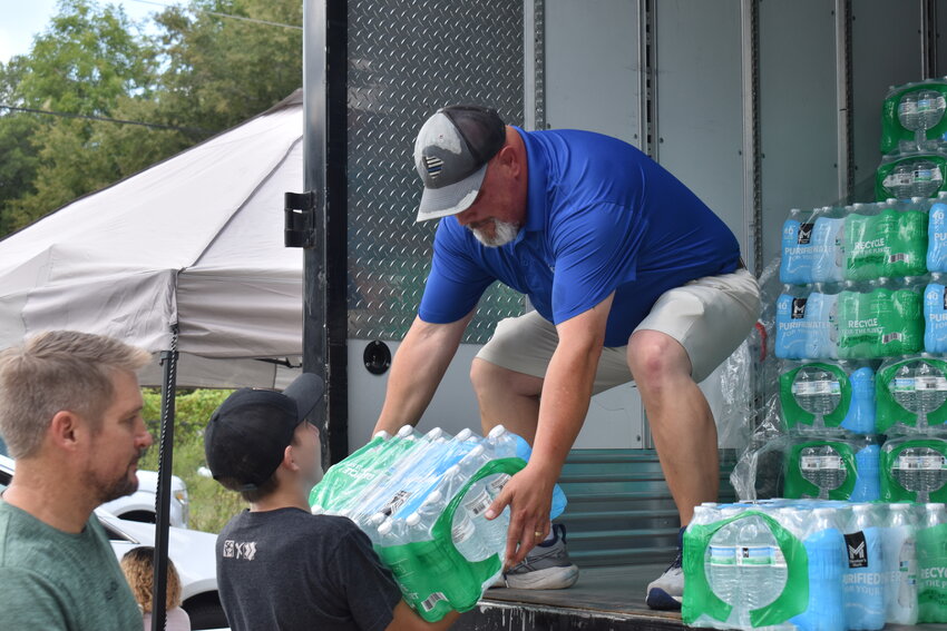 Councilman Eric Moody hands a case of water to a volunteer at the town's first water distribution event over Labor Day weekend. 