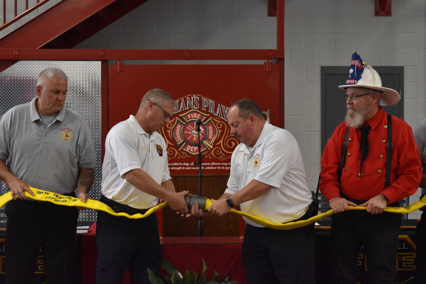 Firefighter Jaime Towne, Assistant Fire Chief Scotty Hankins, Fire Chief Phillip Delk, and retired fire chief Tony Dicks uncouple a firehose at the grand opening of the new department.