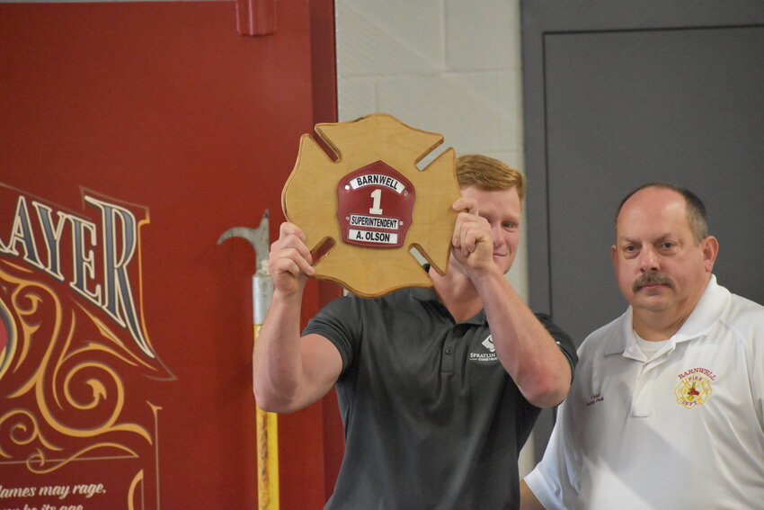 Andrew Olson holds up the plaque presented to him by the city for his dedication to the construction process. Olson served as superintendent on the site for Spratlin & Sons Construction. 