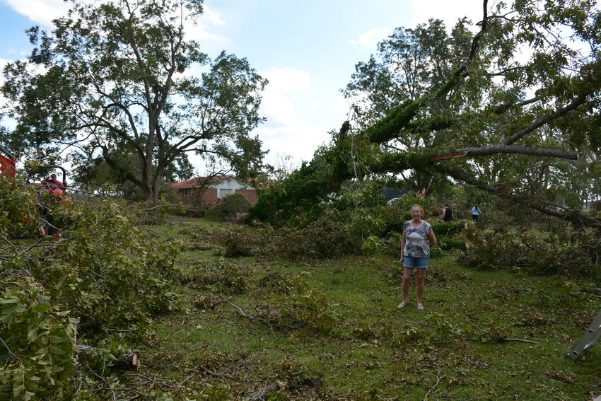 Wilda Carden stands in front of a large tree that fell on her home. Several others fell in her yard.