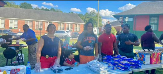 As Blackville police chief Shawn Howze grills in the background, Blackville police officers and Blackville-Hilda High School
football players unite to hand out free hotdogs to the community on September 30.