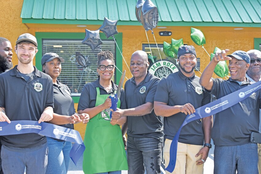 Staceyann Palmer, owner of the new Jam Rock Kravinz, celebrates with her employees after cutting the ribbon at their grand opening on September 9.