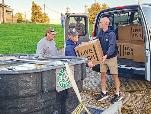 Texas Parks & Wildlife Department’s (TPW) Inland Fisheries Jasper District Supervisor Todd Driscoll hands a box containing 50,000 fry to TPW Inland Fisheries Biologist Dan Ashe as TPW Technician Ray Lenderman waits in the wings. Photo by Emily Banks Wooten.