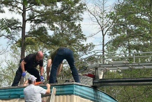 Emergency personnel assist a man who had been trapped on a rooftop.