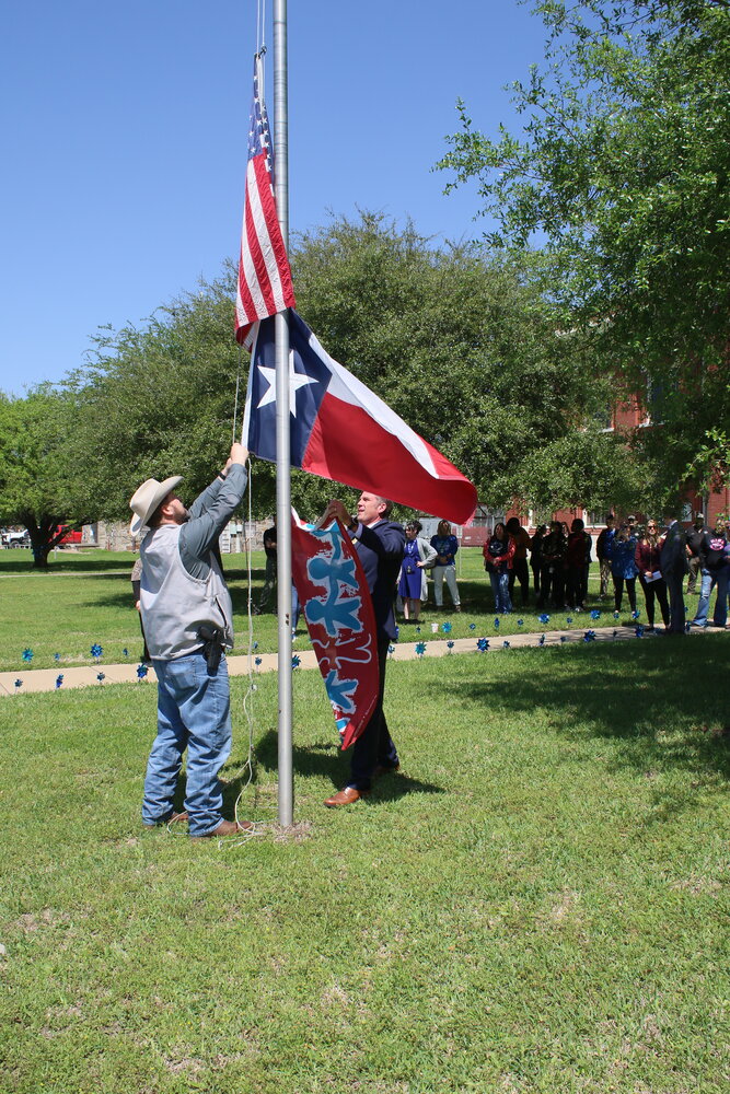 District Attorney Bennie Schiro and Constable Mark Jones raise a flag that commemorates April as Child Abuse Awareness Month.