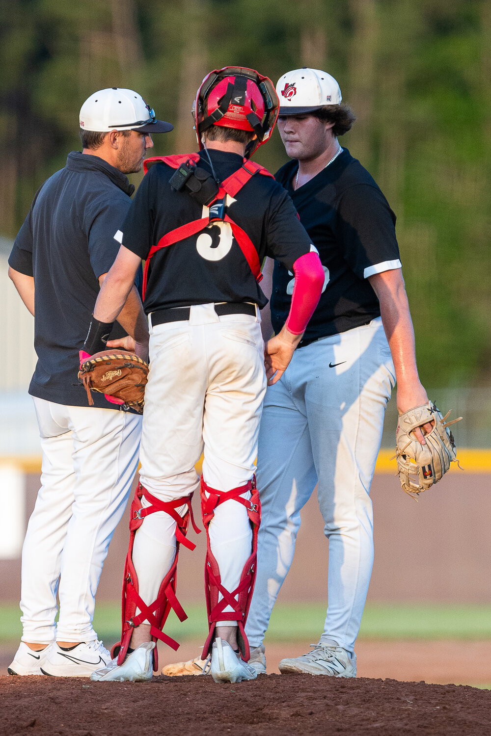 Coach Austin Riddell and catcher Jacob Ash approach the mound to discuss the strategy of the next few pitches with Kaden Hubbard.