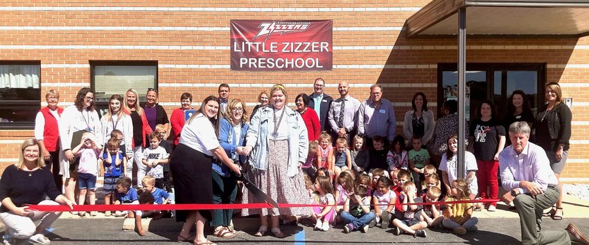 West Plains Elementary&rsquo;s Little Zizzer Preschool celebrated its expansion with a ribbon cutting, held by the Chamber of Commerce on Wednesday. Holding the scissors are preschool teachers Hannah Beaulieu, left, Mary Beth Palmer, center, and Ashley Freeman. Holding the ribbon are chamber ambassadors Heather Kamp, left, and Bryan Adcock. PHOTO BY LORI AMOS