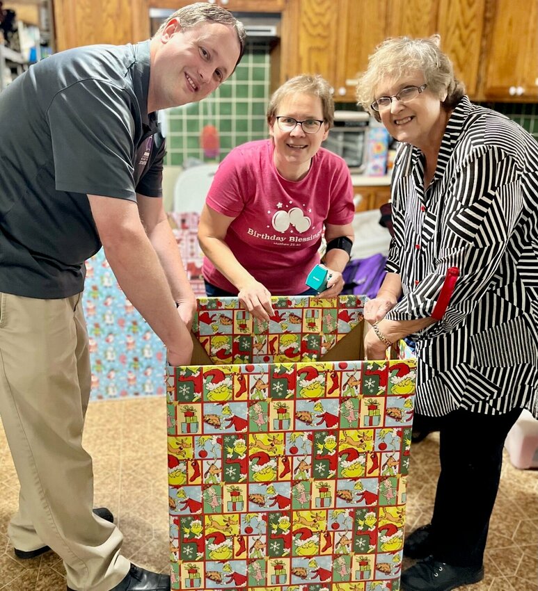 From left, CJ Collins, executive director of Always a Future for Kids; Shannon VonAllmen, executive director of Birthday Blessings; and Connie Pendergrass, executive director of 37th Judicial Court Appointed Special Advocates team up to wrap a collection box in festive holiday paper. Their organizations have teamed up with fellow child advocacy nonprofits Mtn. View Missouri Community Betterment Program and The Chaos Closet to host a toy drive through Dec. 11 with collection sites available in West Plains, Pomona and Mtn. View.