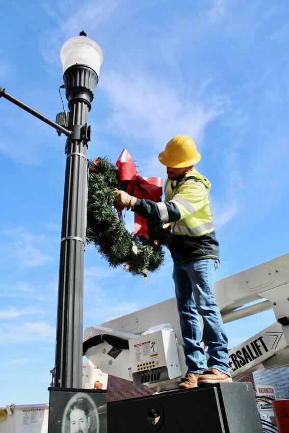 Phillip Brege, city electric department employee, checks and changes bulbs on a Christmas wreath downtown. Three city crews were out Monday under blue skies and in warm temperatures, getting West Plains spruced up for the holiday season. Drivers around town may have noticed some of the snowflake lights that grace the city's main streets have also started going up, and the city Christmas tree will go up at the end of November. As of today, Christmas is only 39 days away.