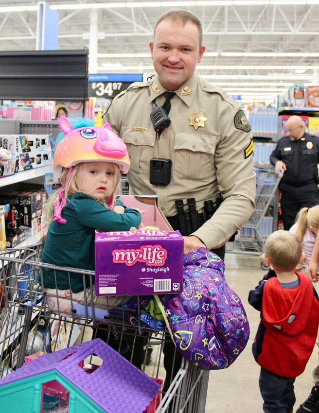 Shop With A Cop was held Saturday morning at Walmart, bringing happiness and holiday cheer to dozens of area children who might otherwise not have a lot for Christmas. Here, Howell County Sheriff's Department Cpl. Seth Smith helped Natalie Hodges, 3, of Koshkonong, choose some items, including some fashionable safety gear. About 110 children were given an allowance of $175 and paired with a public safety or law enforcement employee to pick out Christmas gifts for themselves or others, sponsored by the Fraternal Order of Police Lodge No. 43. Donations were made by Walmart, local businesses and private citizens, and recipients were determined by need. Participating agencies were the Howell County Sheriff's Office, West Plains Police Department, Mtn. View Police Department, Missouri State Highway Patrol, Missouri Department of Conservation, Missouri State Fire Marshal's Office and State Fire Marshal Tim Bean, South Howell County Ambulance, Air Evac Lifeteam, West Plains Fire Department, Howell County Rural Fire Department, Pomona Fire Department and the 37th Judicial Circuit Juvenile Office. For more festive photos, turn to page A5 of today&rsquo;s Quill to see highlights from the West Plains Christmas Parade, and watch Saturday&rsquo;s Gazette for snapshots from Cookies with Claus, both events having also happened Saturday.