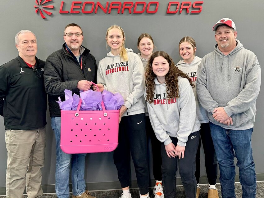 Leonardo DRS, Inc., of West Plains, has once again stepped up in support of Lady Zizzer Basketball by donating an item for live auction during halftime of the Varsity Pink Out Game, set for Thursday at West Plains High School. Donated was a pink Bogg Bag beach bag, filled with items including Bogg koozies and a pink blanket. Thanks to the generous donation by DRS, all proceeds raised from this item during the live auction will be donated directly to the Ozarks Healthcare Cancer Treatment Center. Pictured, from left, are Lady Zizzer Head Coach Scott Womack; Stephen Foster with DRS; Lady Zizzers Allyssa Joyner, Ashley Culton, Aubrey Tidwell and Cameron Brill; and Bruce Vincent with DRS. For additional information, visit the 2024 Lady Zizzer Basketball Pink Out Game and Fundraiser event page on Facebook. To support the fundraiser, visit the online store at&nbsp;www.ladyzizzerpinkout.squarespace.com.