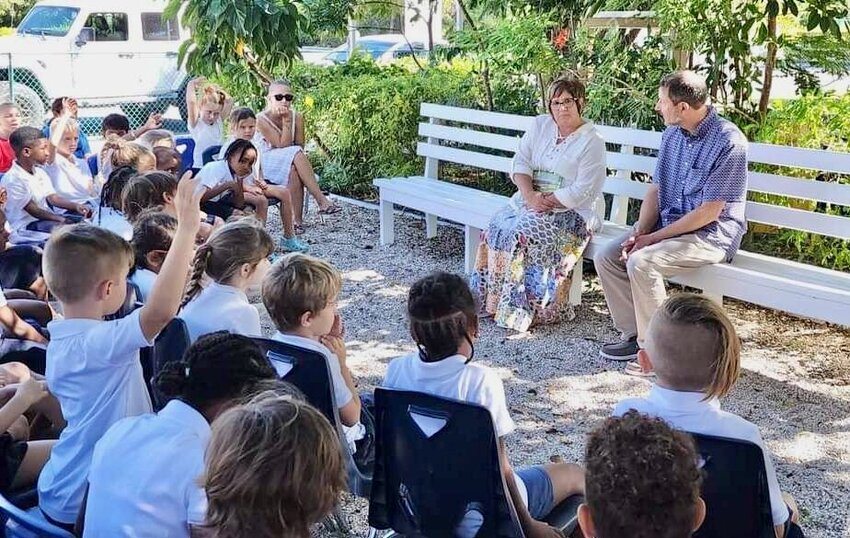 Local author Jill Pietroburgo recently had the unique experience of reading her children's book &quot;Sometimes Grandma Calls Me Jean&quot; at the International School of Turks and Caicos, a British territory located in the Caribbean. Seated next to her on the right is her husband, Phil Pietroburgo. She was inspired to write the book after her mother, Bonnie Sullivant, was diagnosed with dementia in 2019. It deals with a young girl's relationship with her grandmother and how it changes after the grandmother's dementia diagnosis, including explanations about the disease and suggestions for families meant to help children understand it, and other memory disorders. The book continues to receive awards and positive reviews for its handling of the topic and quality writing and illustration.