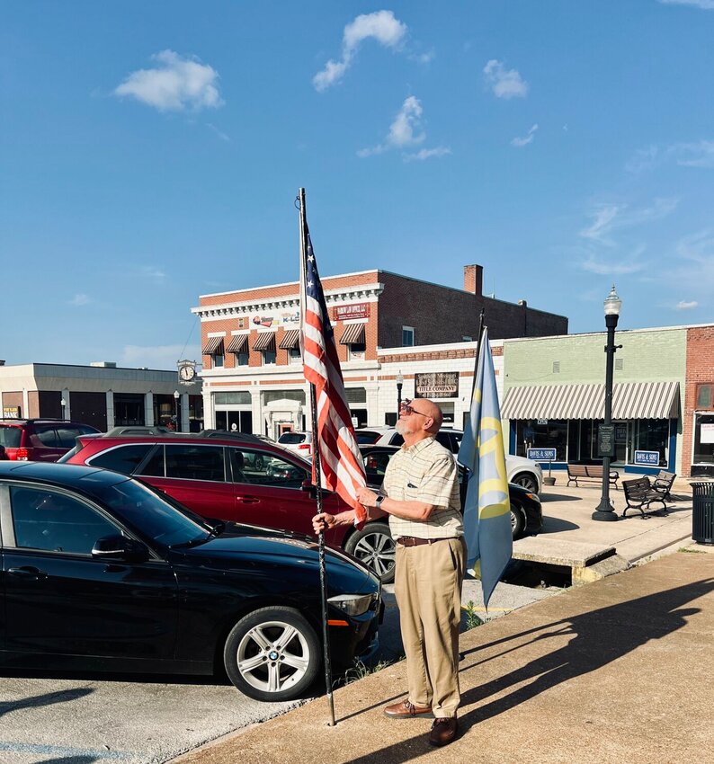 Toney Aid lowers the American flag in front of Aid Downtown Antique for the final time on Saturday.