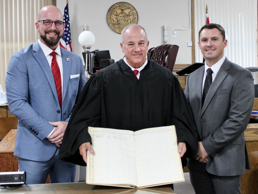 For the record, West Plains attorneys Seth Owens, left, and John Williams, right, have signed the historic register of attorneys at the Howell County courthouse and were sworn in by Presiding 37th Judicial Circuit Judge Steven Privette, center. As such, they are now officially registered to practice law in Howell County. Owens came to the profession after 13 years of being a physical therapist, and it was his experience with patients and their struggle with qualifying for benefits that inspired him to become an attorney to assist veterans. Williams has joined his father Roy Williams at the Henry, Williams & Kinder, P.C. law firm. His focus will be personal injury litigation.